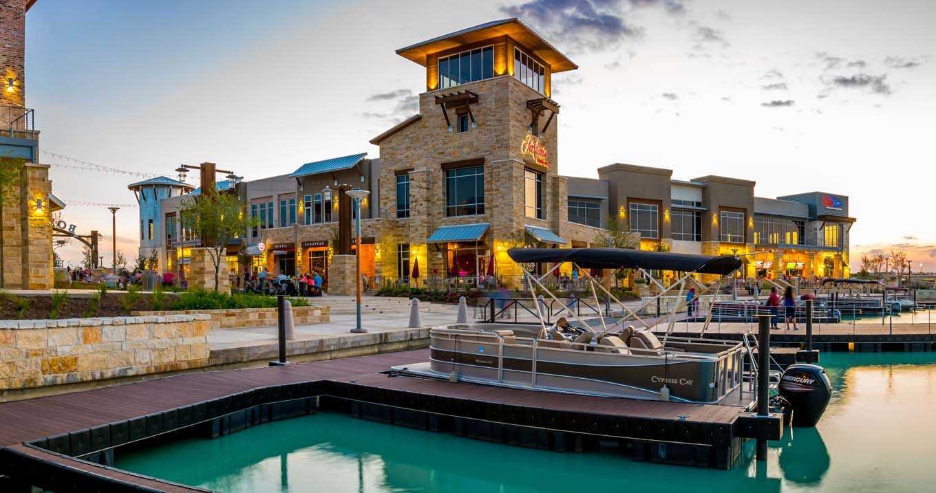 Waterfront shops and restaurants with a pontoon boat at a dock in Cypress
