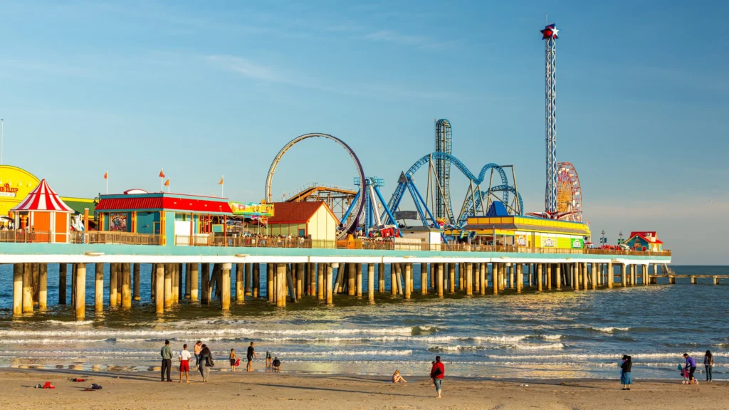 Galveston Pleasure Pier rides above the Gulf with beachgoers along the shore