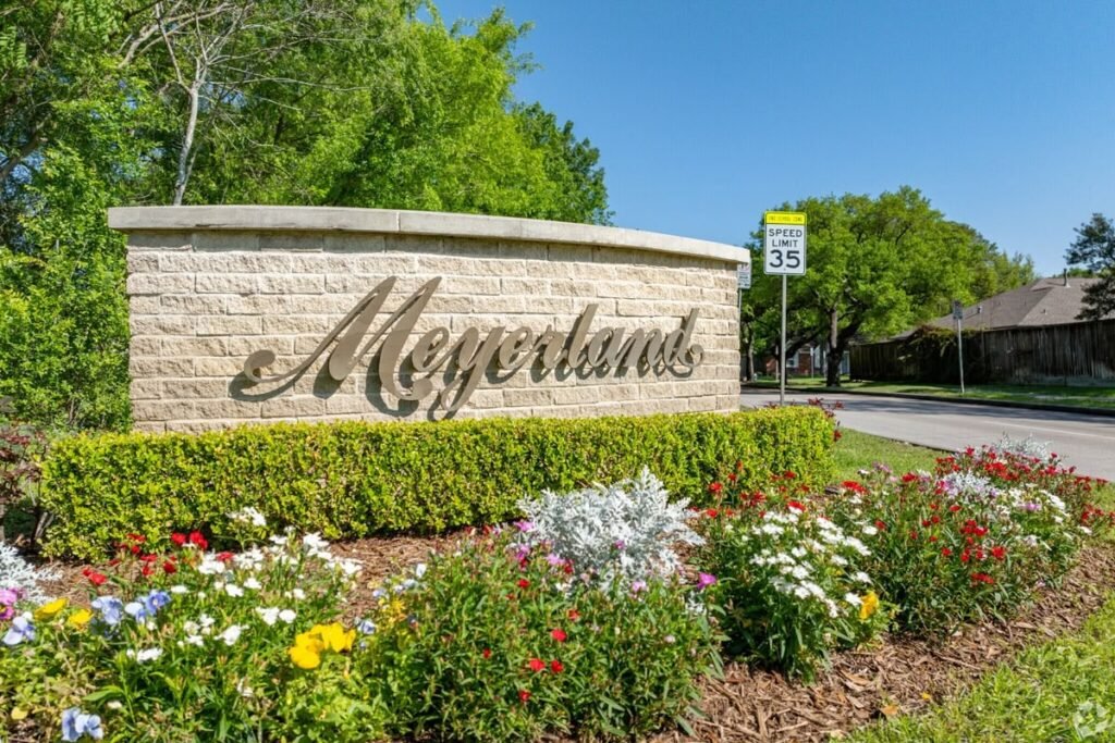 Meyerland stone neighborhood sign surrounded by flowers and trees