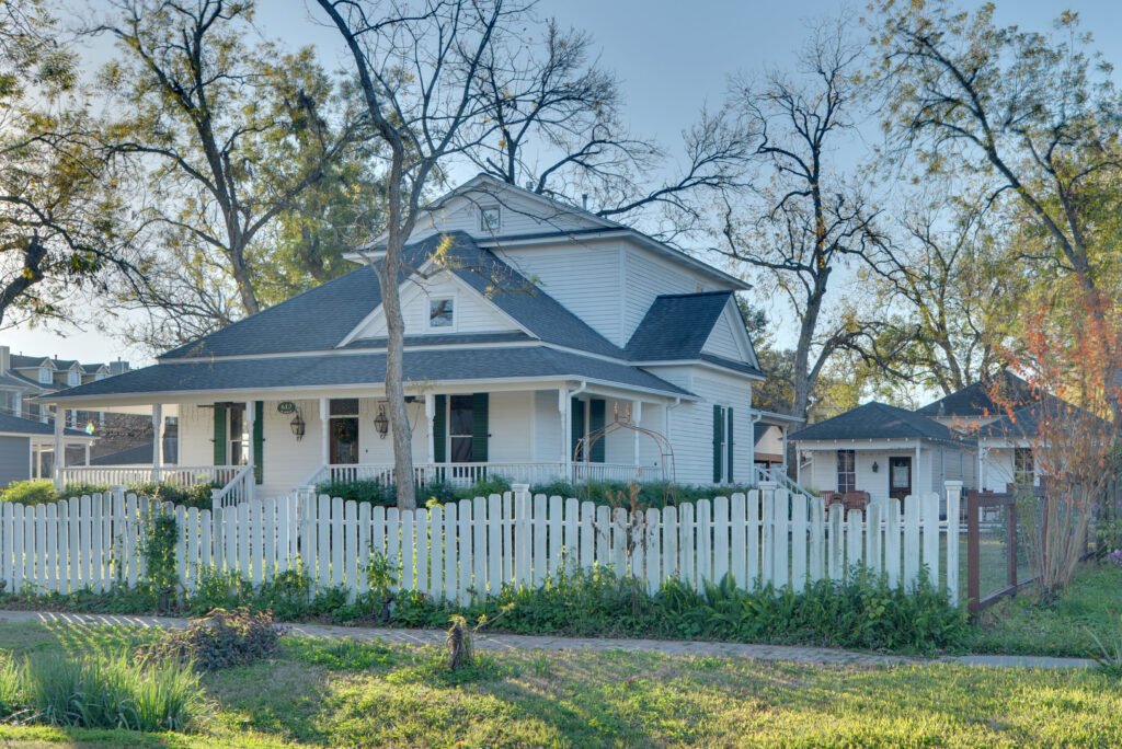 White wood-sided Kronenberger House with a wraparound porch and picket fence, photographed in Houston Heights in December 2010.