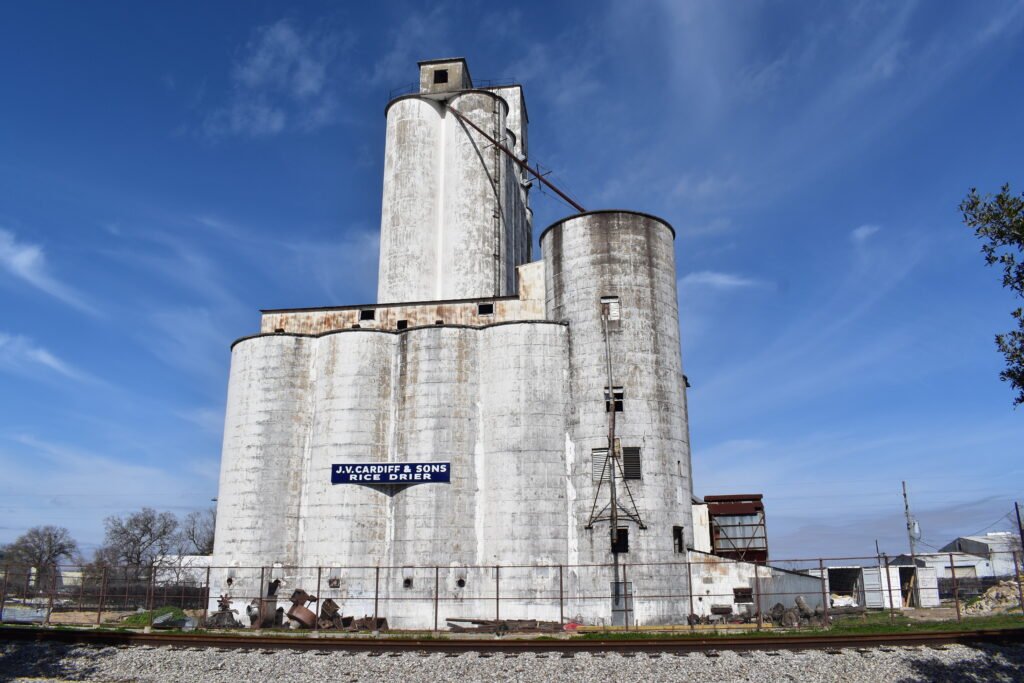 Historic white rice dryer silos beside railroad tracks in Katy, Texas