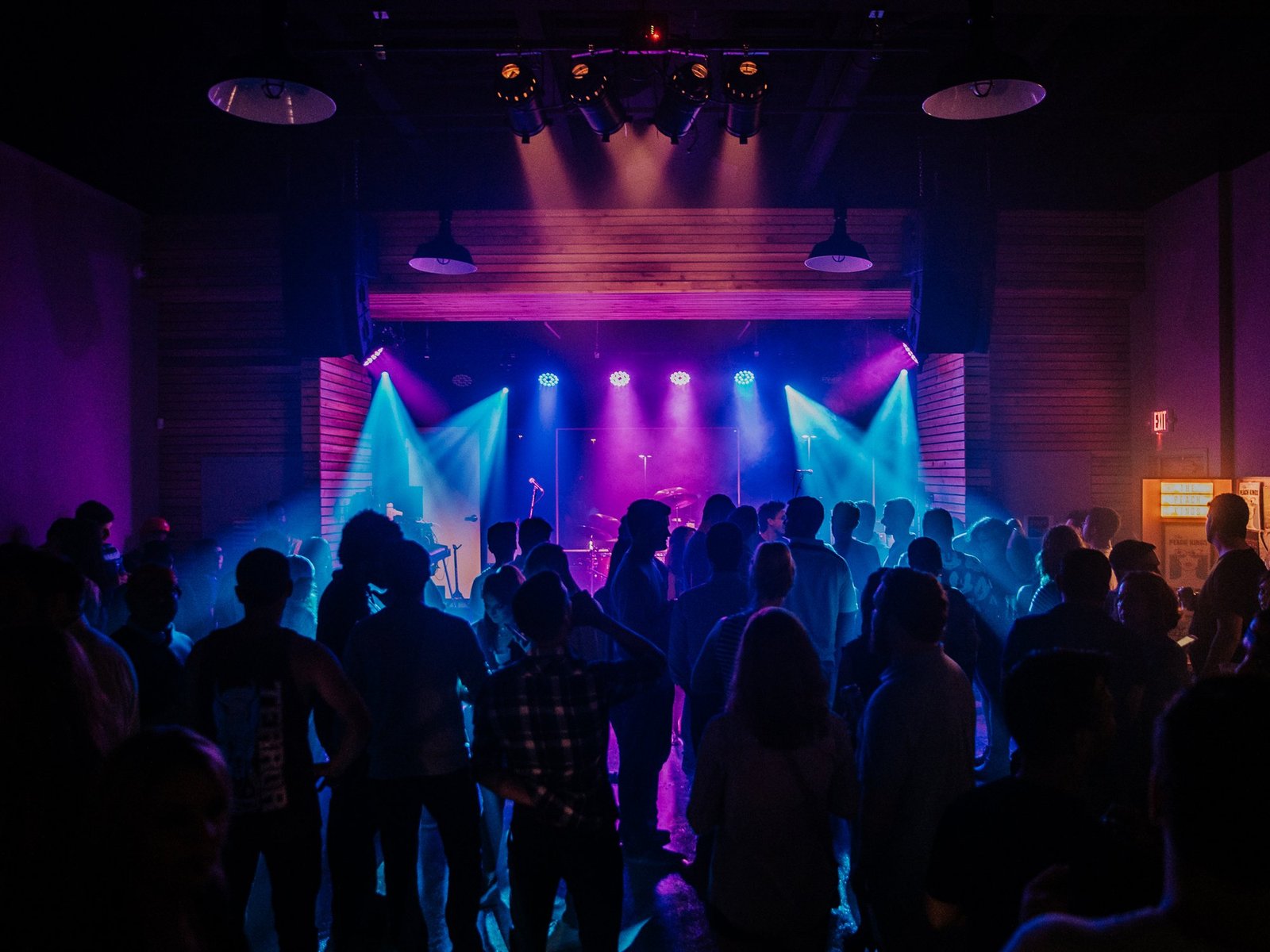 Crowd facing a stage lit in purple and blue inside White Oak Music Hall's main room