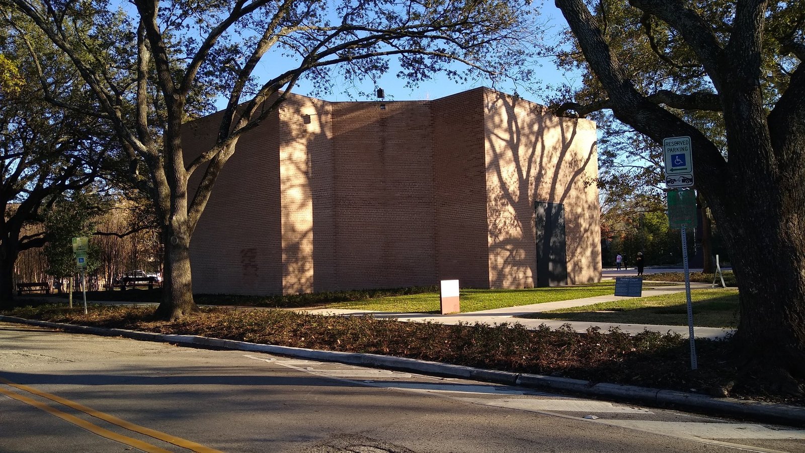 The windowless brick exterior of the Rothko Chapel in Houston, framed by live oak trees
